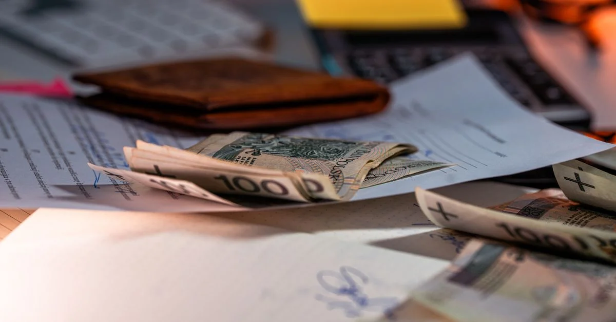 Billets de zloty et documents financiers éparpillés sur un bureau, représentant le budget et la finance.