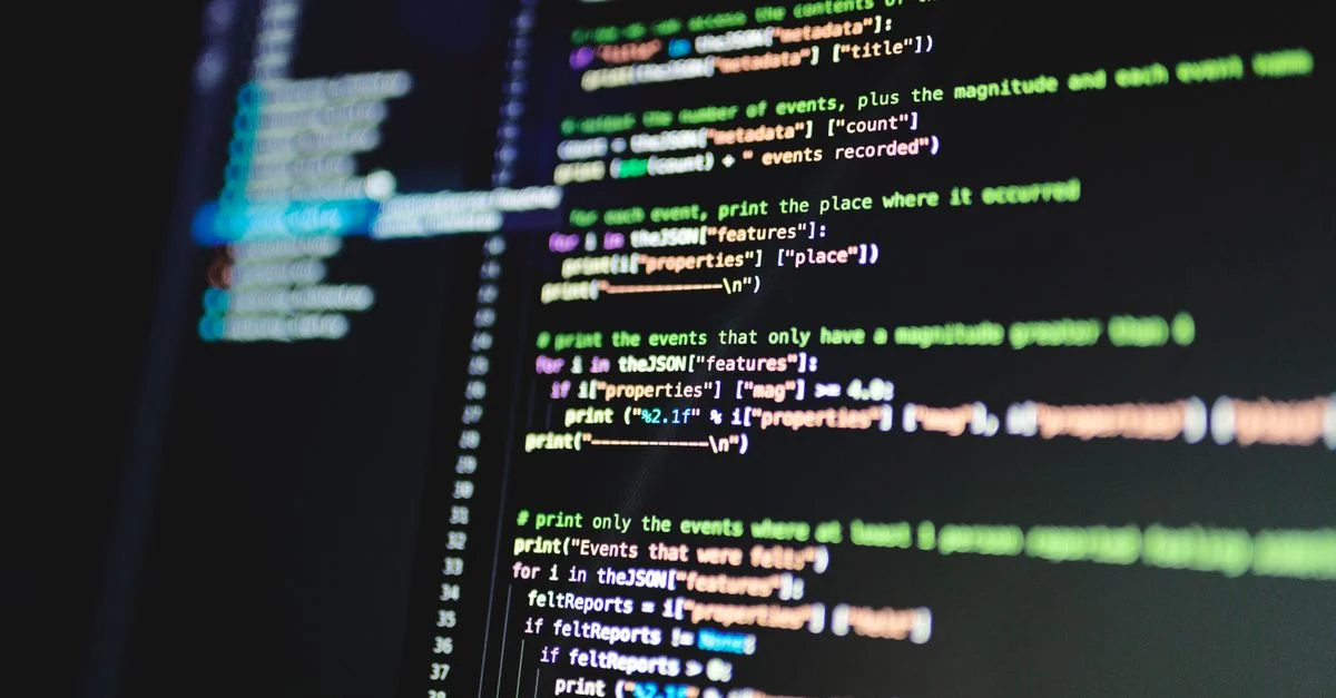Gros plan sur du code de programmation coloré affiché sur un moniteur d'ordinateur avec un fond sombre.