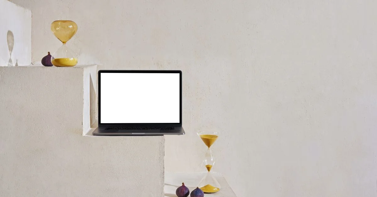 Une scène minimaliste avec un sablier, un ordinateur portable et des figues sur un escalier.