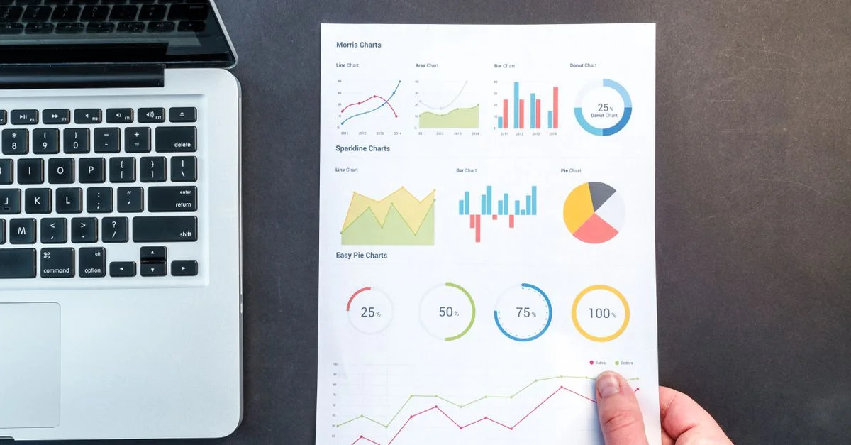 Graphiques et diagrammes détaillés sur un document à côté d'un ordinateur portable, représentant une analyse de données.